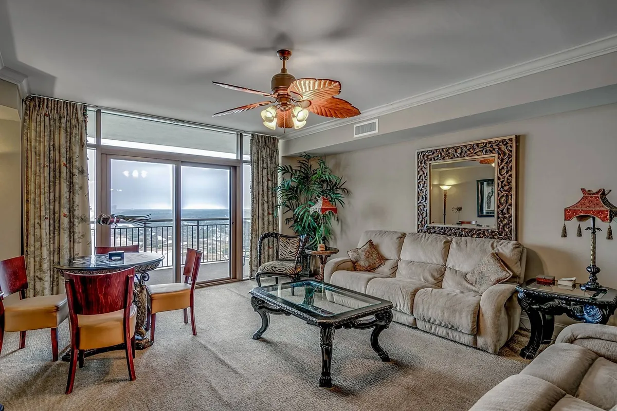 A spacious, open-concept living and dining area with large windows framing breathtaking ocean views. The scene features a stylish dining table set for gathering, a comfortable sofa perfect for relaxing, and a decorative mirror that adds elegance and depth to the space. Natural light fills the room, highlighting the cozy, inviting atmosphere ideal for family time or entertaining guests.