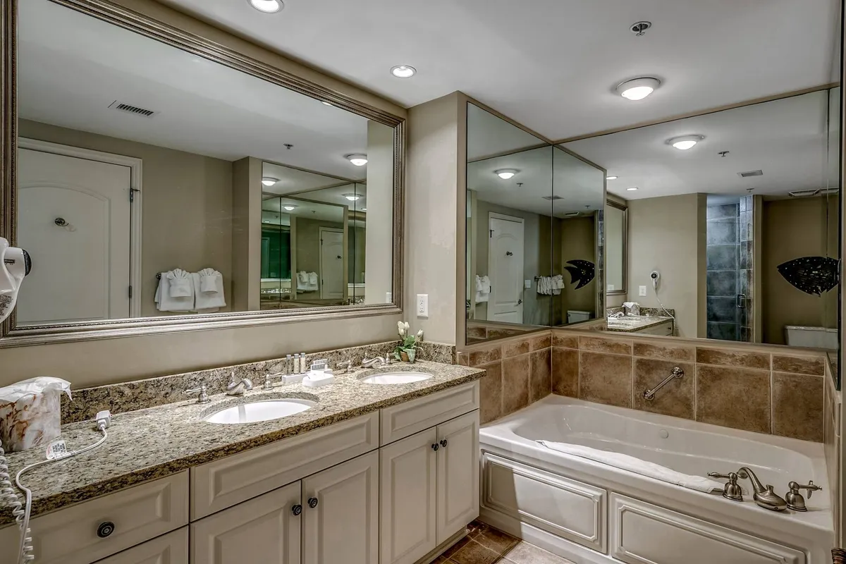 A serene ensuite bathroom featuring a double sink vanity, large mirror, bathtub, and a separate shower area. The space is bright and tranquil, ideal for self-care routines or a relaxing soak after a busy day.