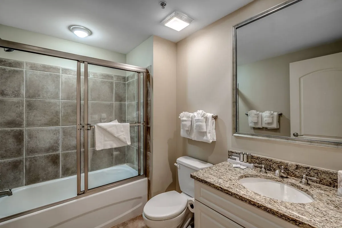 An elegant, spa-like bathroom interior with a glass shower enclosure, granite countertop, and a large mirror, creating a serene and rejuvenating space.