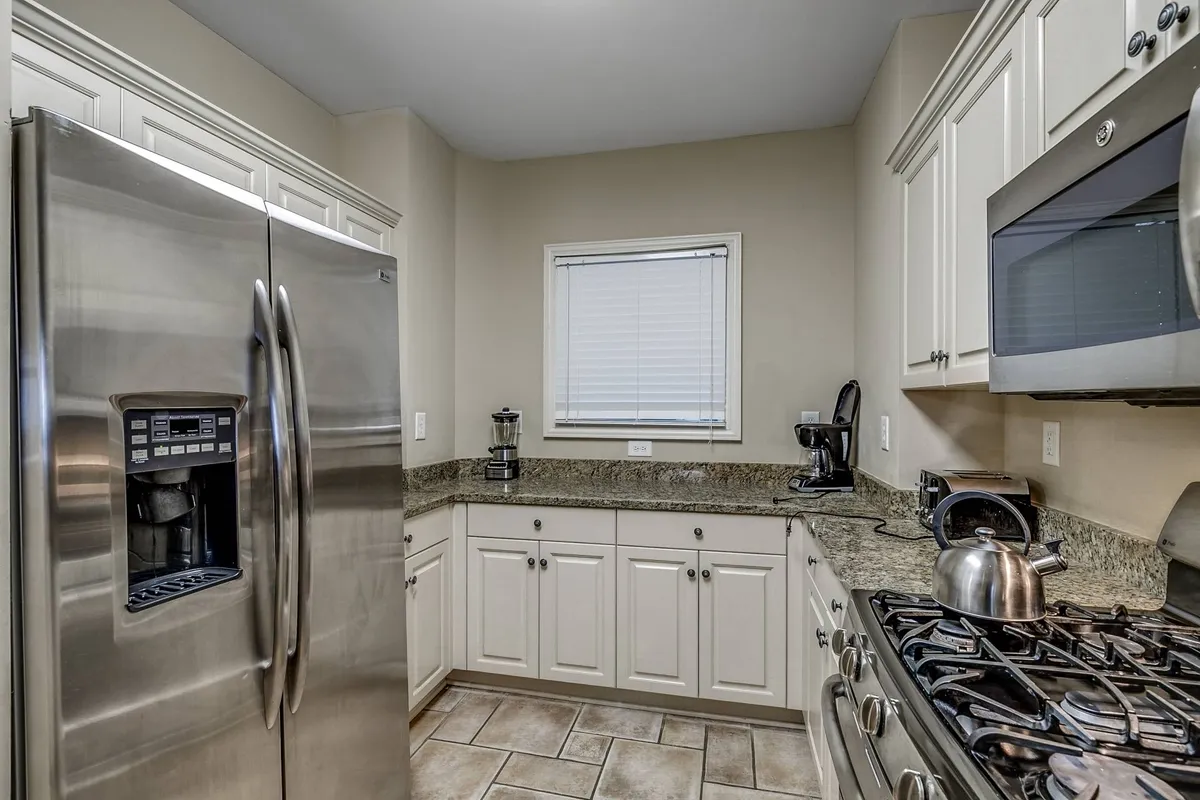 A warm and functional kitchen is depicted here, focusing on a large stainless steel refrigerator, granite countertops, and a gas stove. The setting hints at lively cooking sessions, baking cookies, and hosting festive dinners, embodying the heart-of-the-home vibe. The design signals both luxury and practicality, underscoring the kitchen’s role as a hub for entertaining and family gatherings.